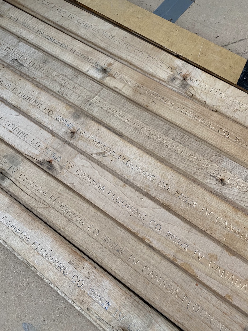Reclaimed Canadian maple boards, still carrying their mill stamps — sorted and prepared before fitting.